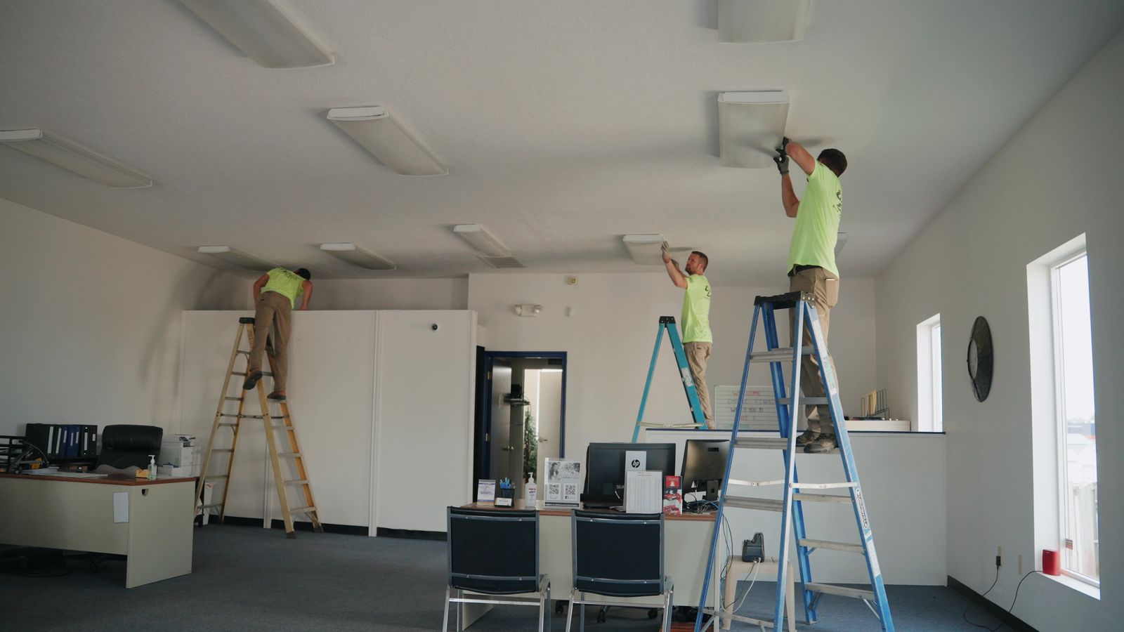 Electricians installing ceiling lighting in a commercial office build-out